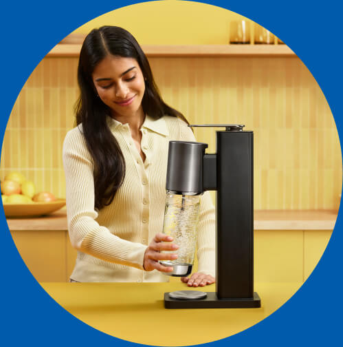 Kobieta montująca butelkę w czarnym saturatorze Sodastream Fresh Plus
